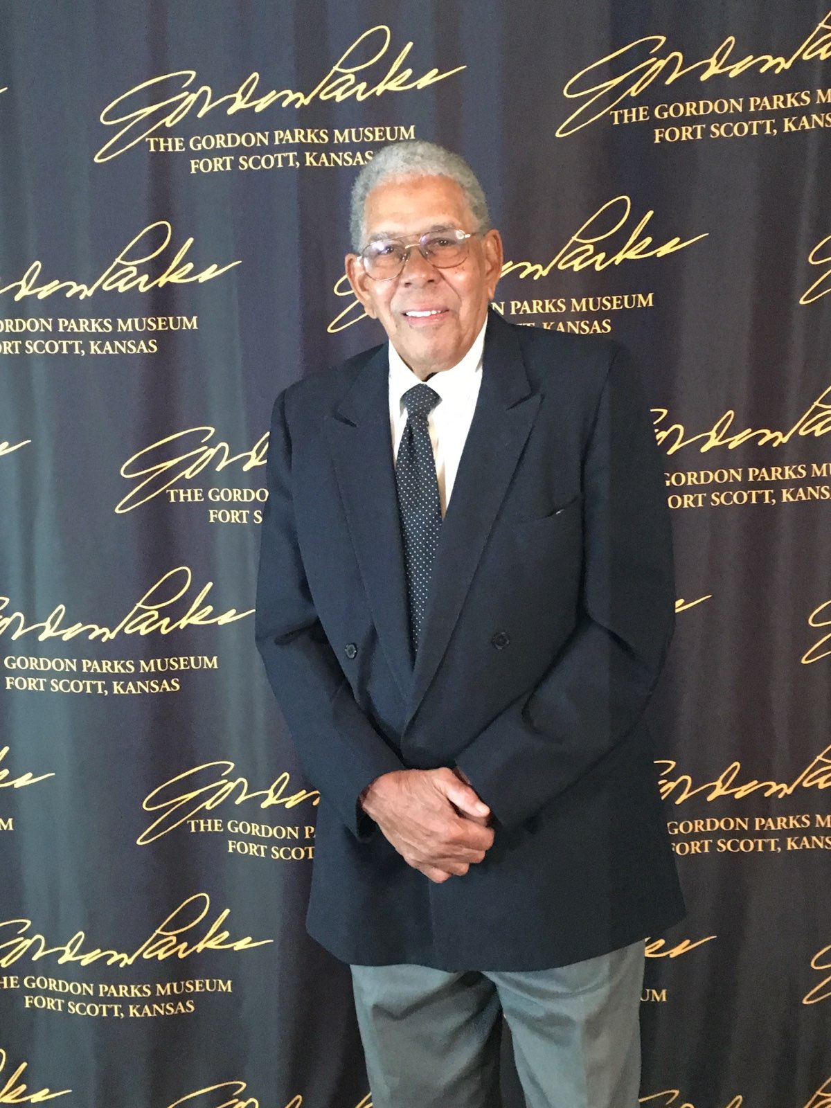 David Parks smiles at camera, wearing a black suit and tie. 