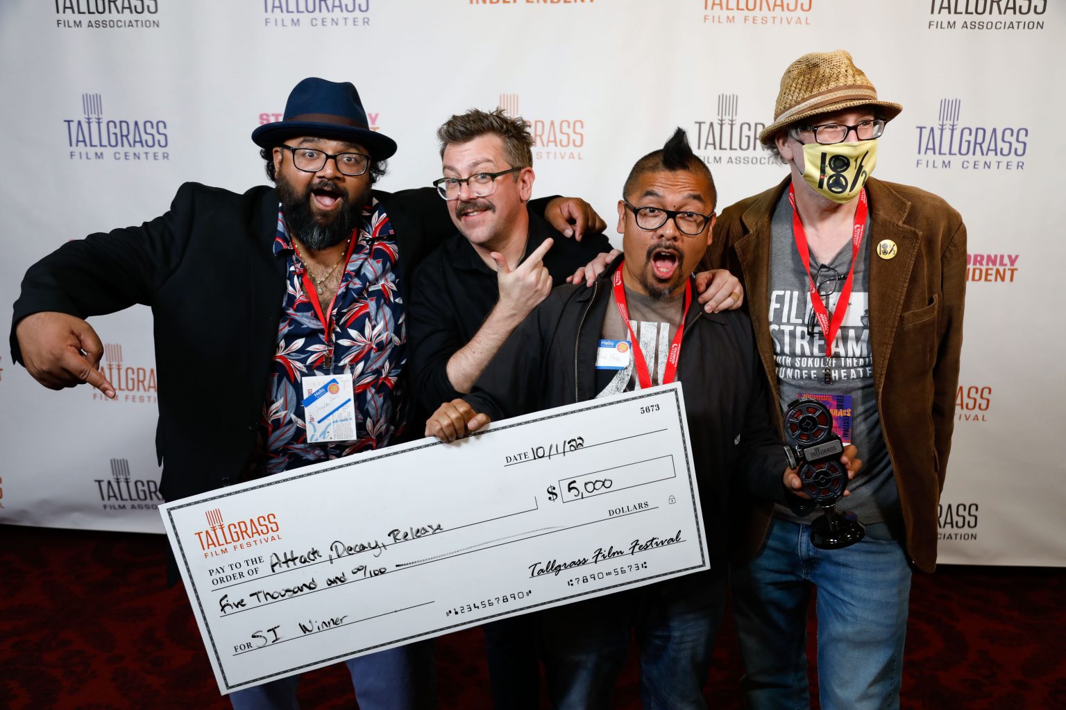 Four men stand in front of camera holding a large check