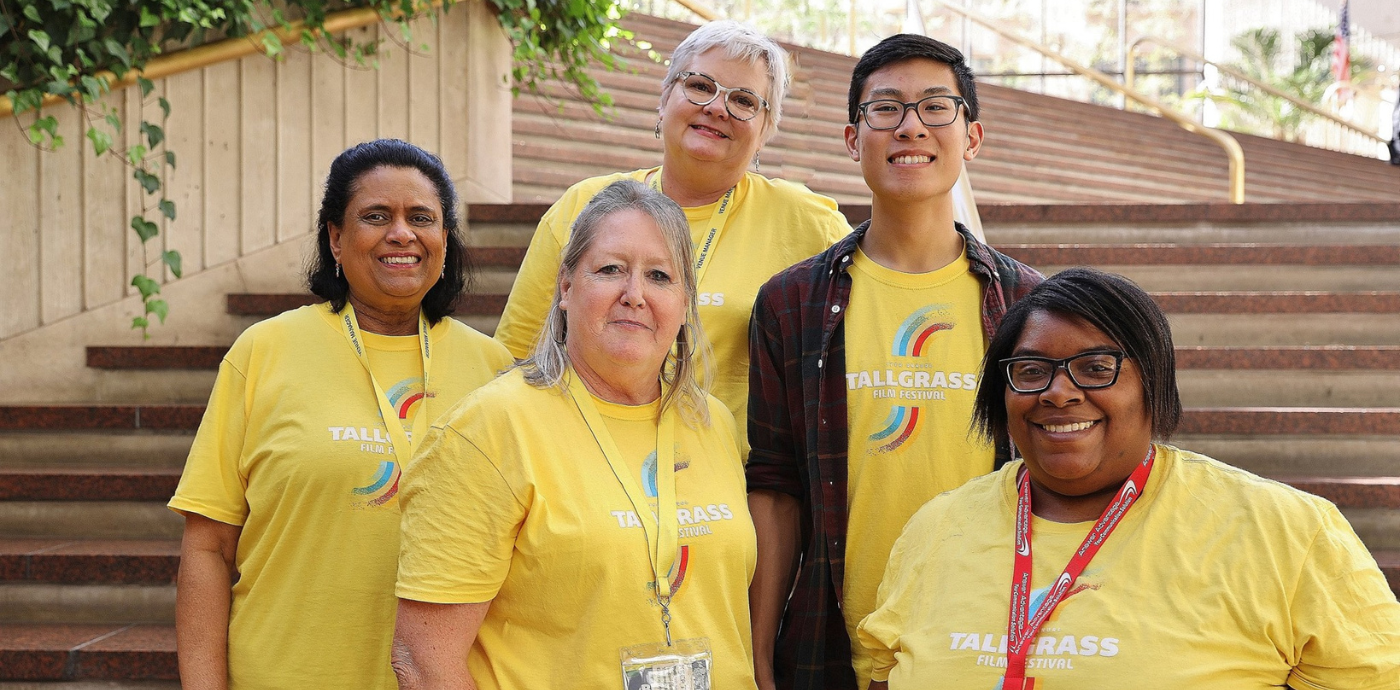 5 volunteers stand in front of a set of stairs wearing bright yellow shierts