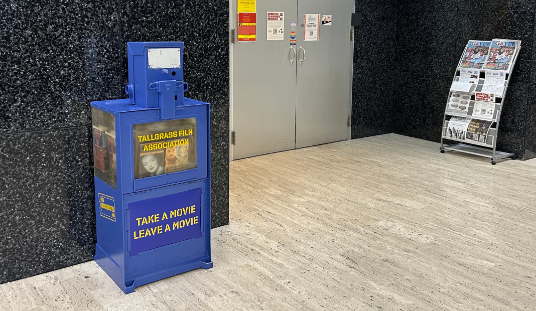 Blue newspaper box filled with movies, labeled Take a Movie Leave a Movie next to a silver door