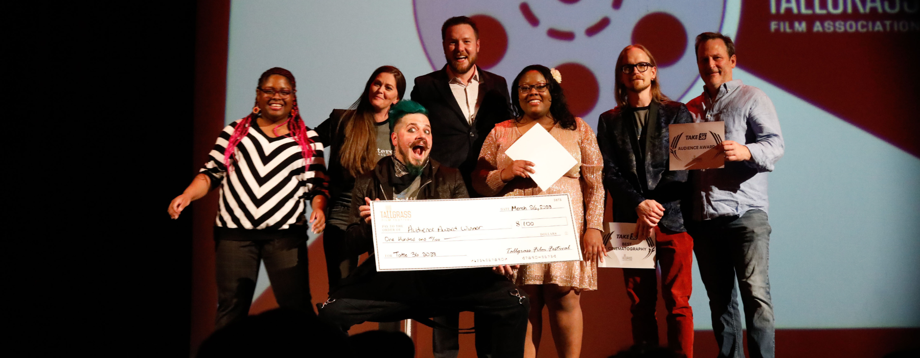 Filmmakers, host and judges pose on stage at the Orpheum with a big check for Audience Award winner at Take 36.