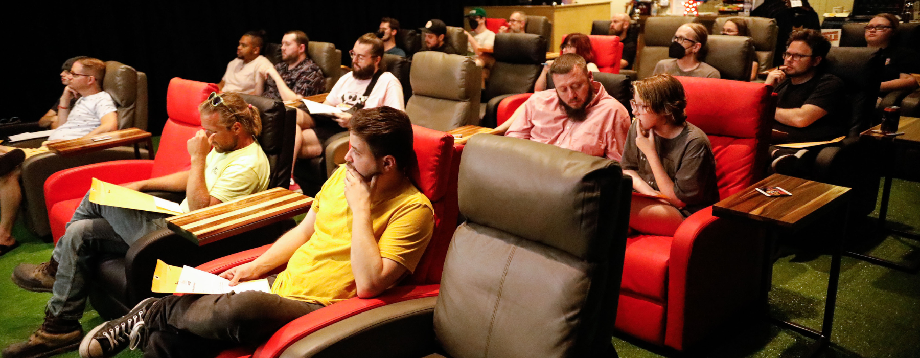Audience sits in recliners in a theatre.