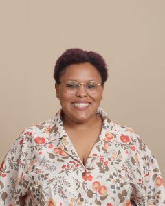 Female smiles at camera and is wearing a peach blossom shirt.